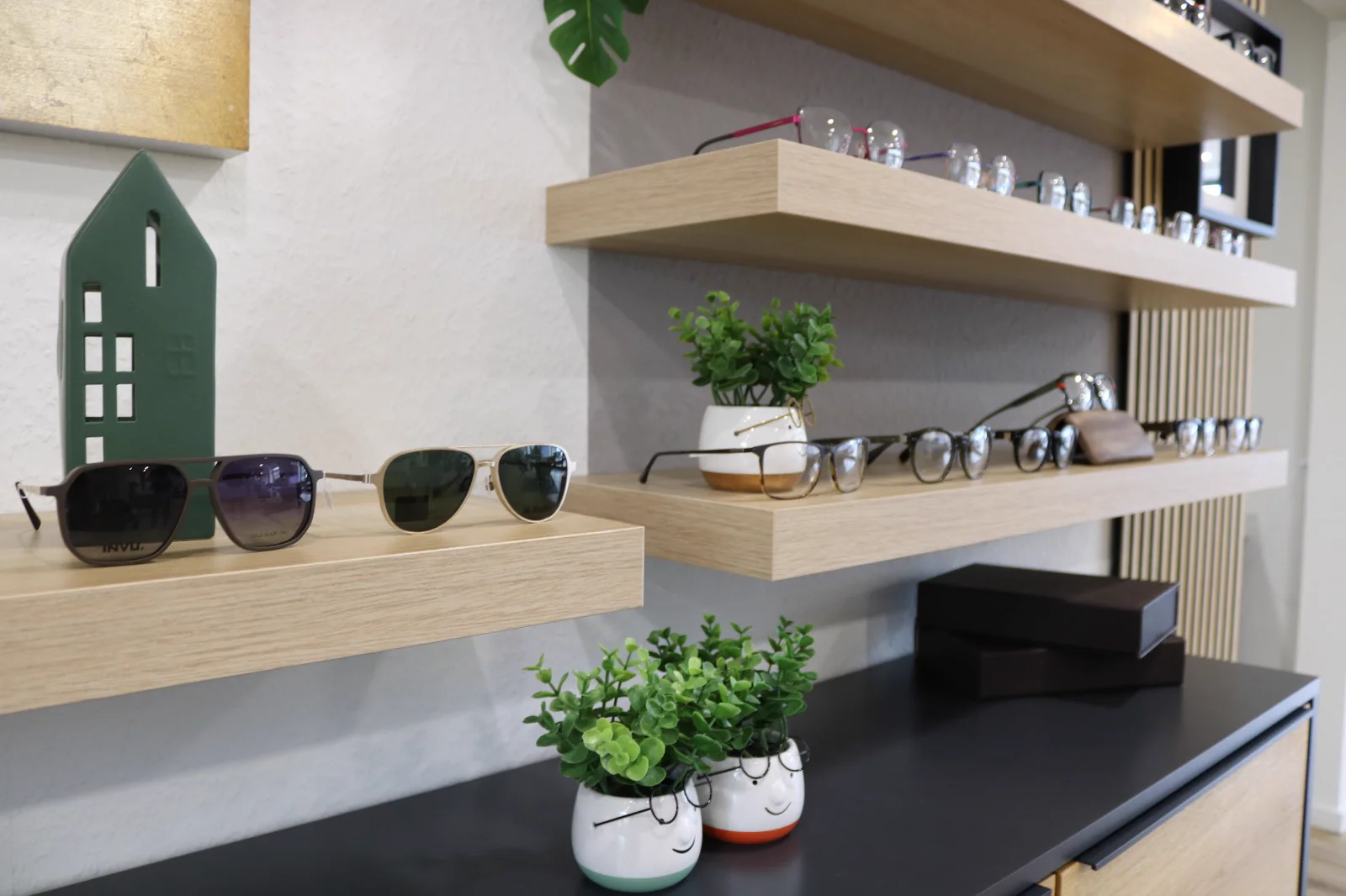 Brillen und Sonnenbrillen bei Augenzuhause Brillenauswahl auf Holzregalen im Augenzuhause Optikergeschäft