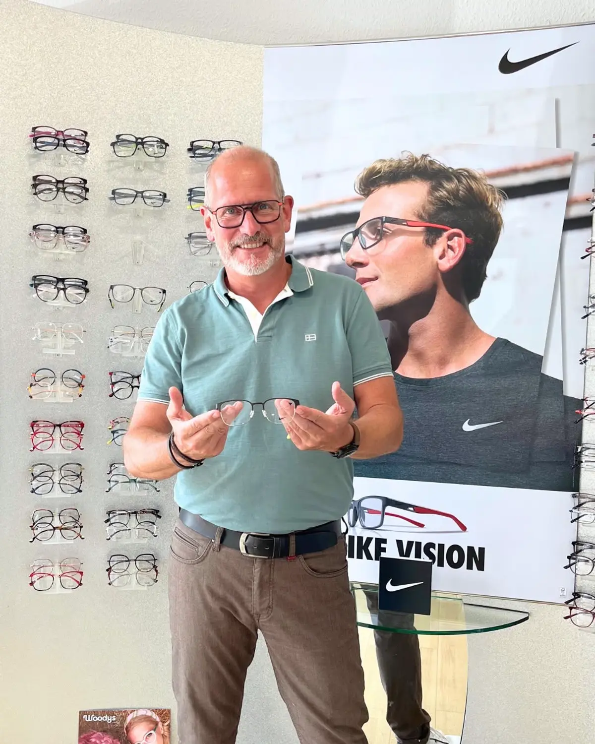 Brillenfassungen bei Augenzuhause Augenoptiker zeigt eine Brillenfassung vor der Fassungswand